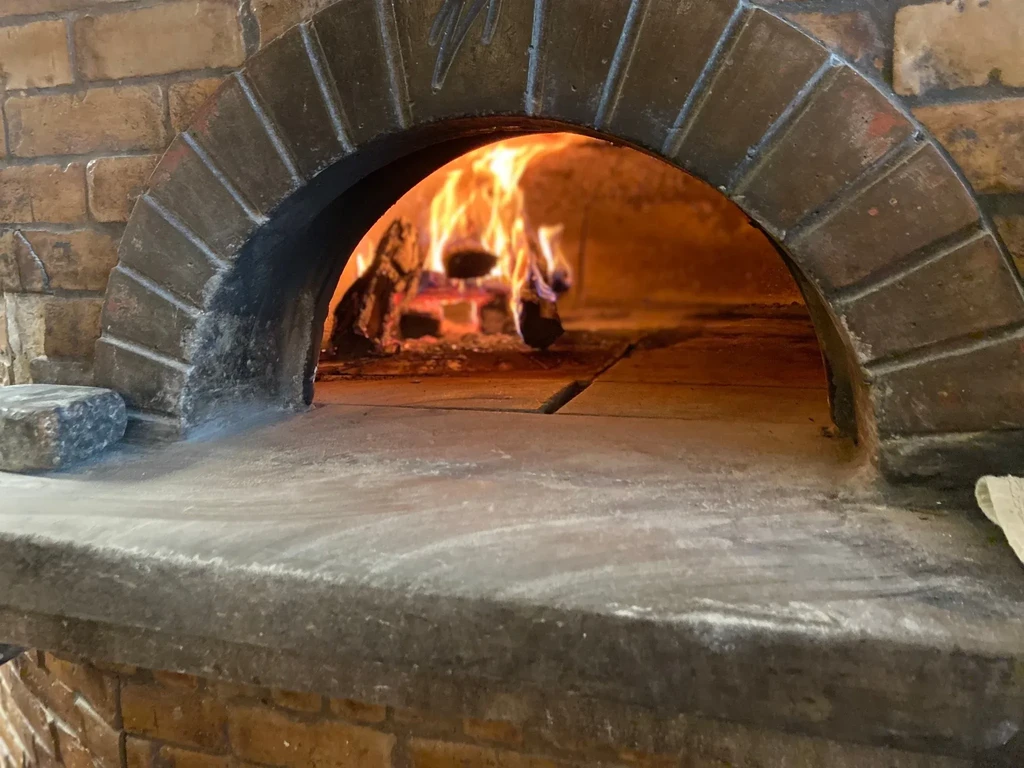 Brick pizza oven with a blazing fire inside.