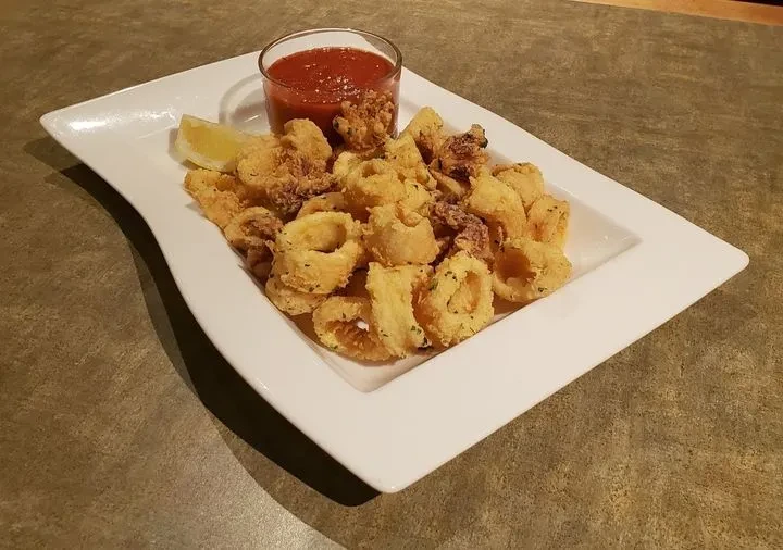 Fried calamari rings and tentacles with dipping sauce and lemon.