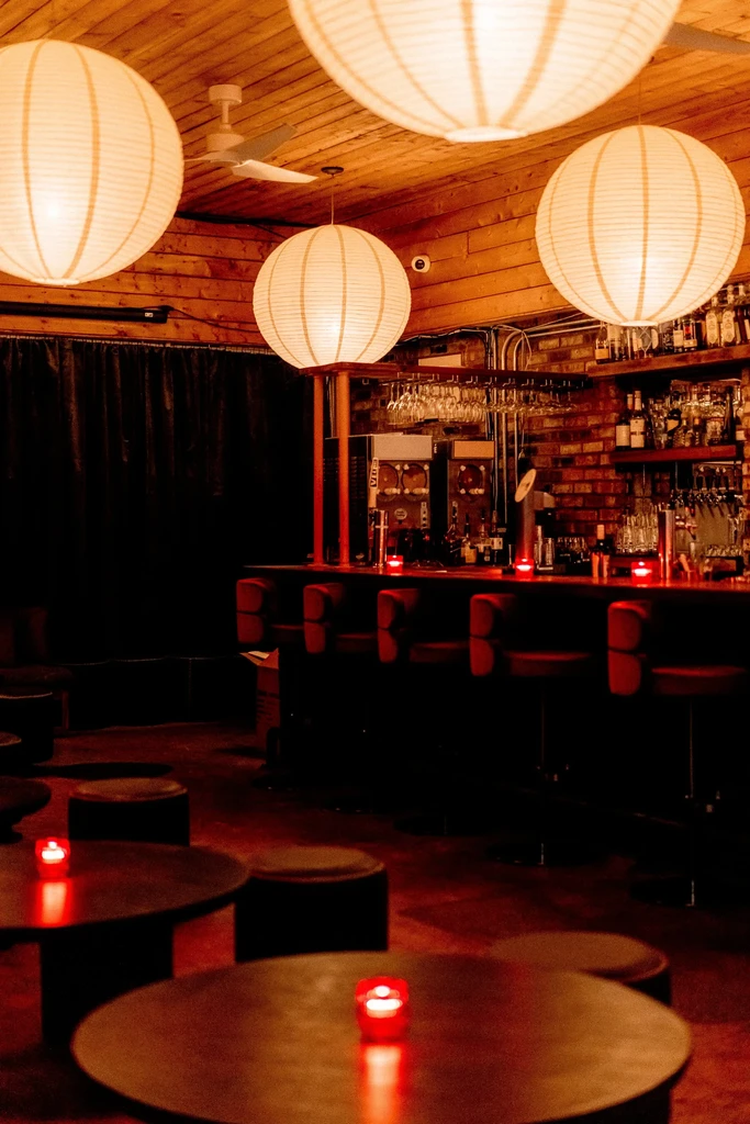 Dimly lit bar interior with paper lanterns and a well-stocked bar.