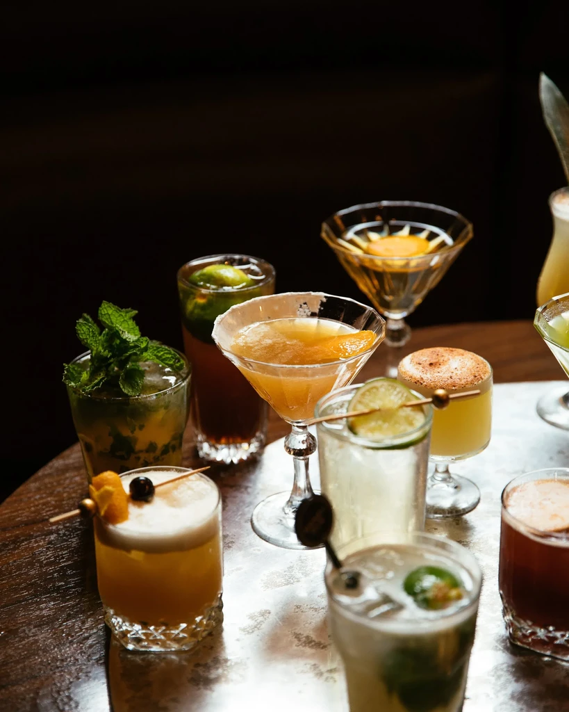 Various cocktails in unique glasses arranged on a tray.