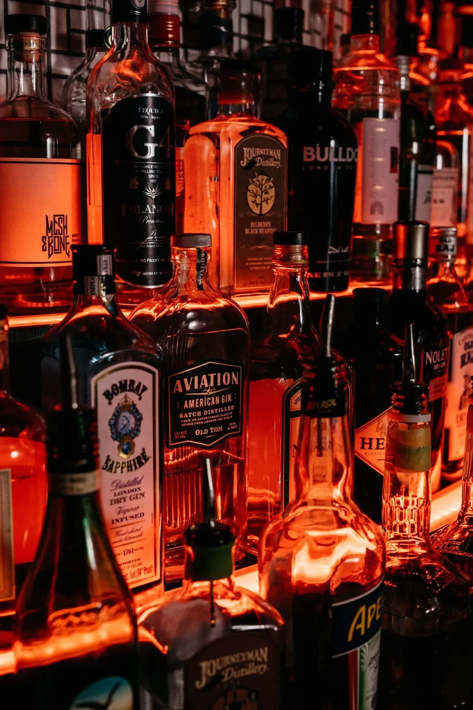 Close-up of assorted liquor bottles with visible labels on a bar shelf.