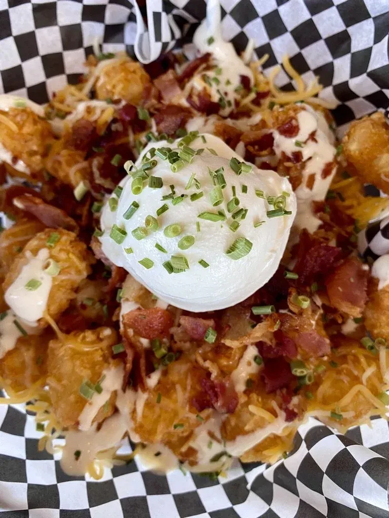 Crispy loaded tater tots with cheese, bacon, chives, and creamy sauce.