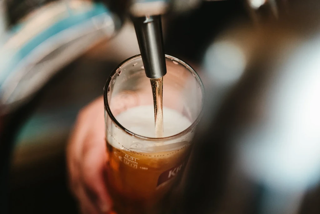 Golden Czech beer pours from tap into a branded glass.