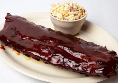 Full rack of glossy BBQ ribs and creamy coleslaw.