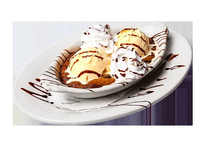 Warm baked good with ice cream, whipped cream, and chocolate drizzle.
