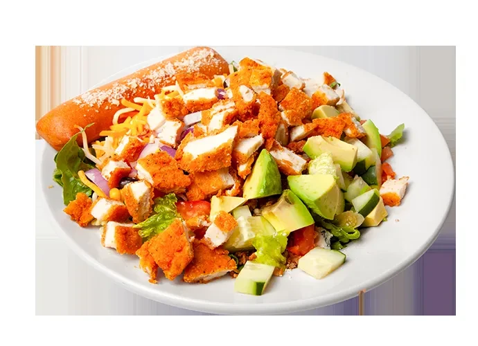 Large salad with crispy chicken, avocado, cheddar, red onion, and breadstick.
