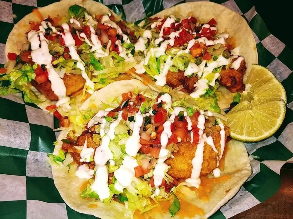 Three fried protein tacos with lettuce, pico, sauce, and lime.