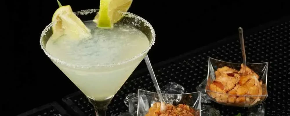 Margarita cocktail with lime and salt rim, plus two appetizers.