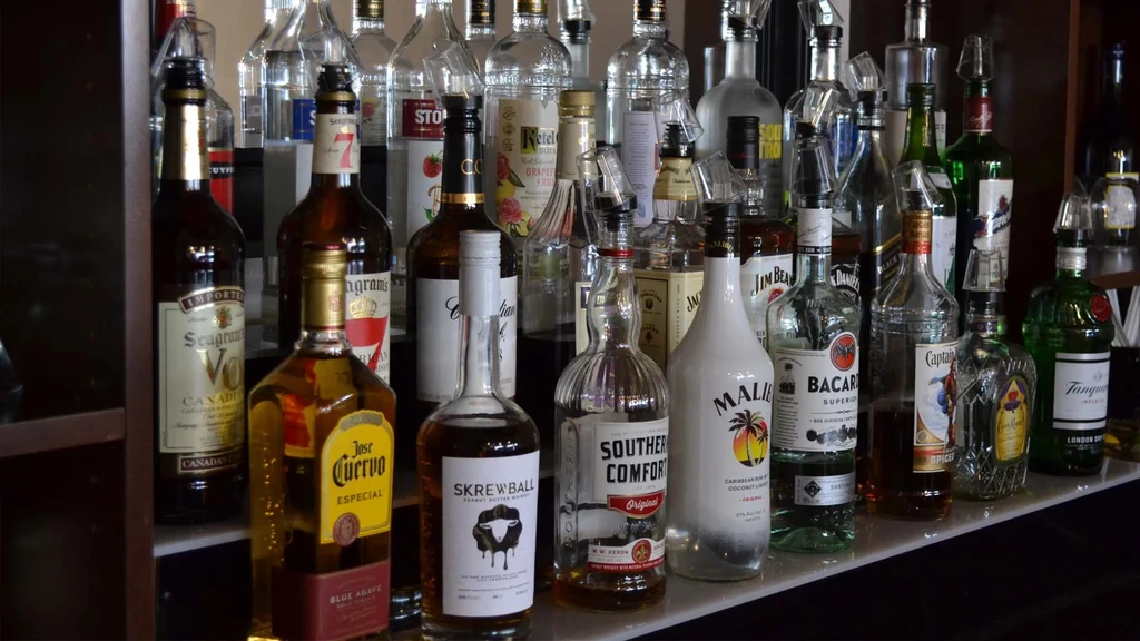 Well-stocked bar counter with numerous liquor bottles and pour spouts.