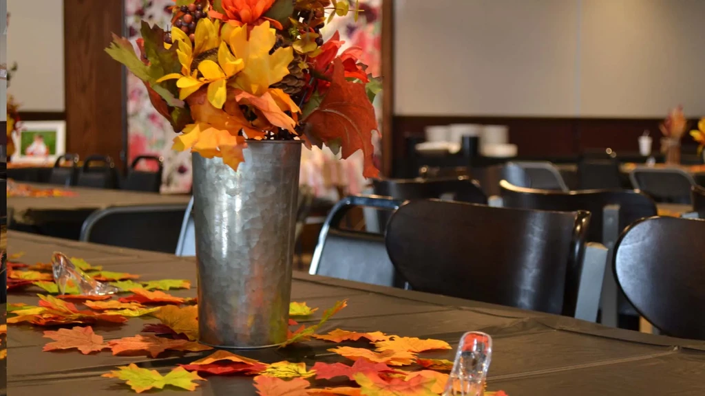 Autumn table setting featuring a rustic vase filled with fall foliage.