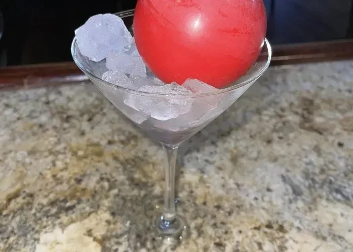 Martini glass with crushed ice and a large red ice ball.