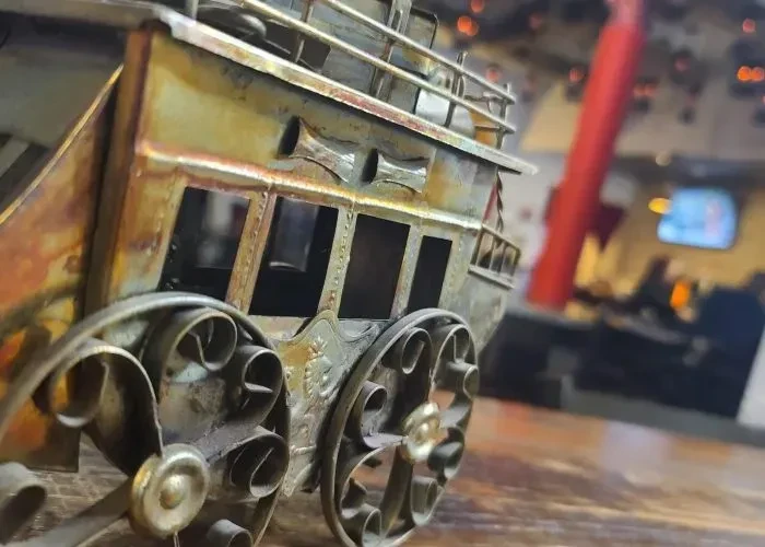 Close-up of an intricate, antique-style brass stagecoach model on wood.