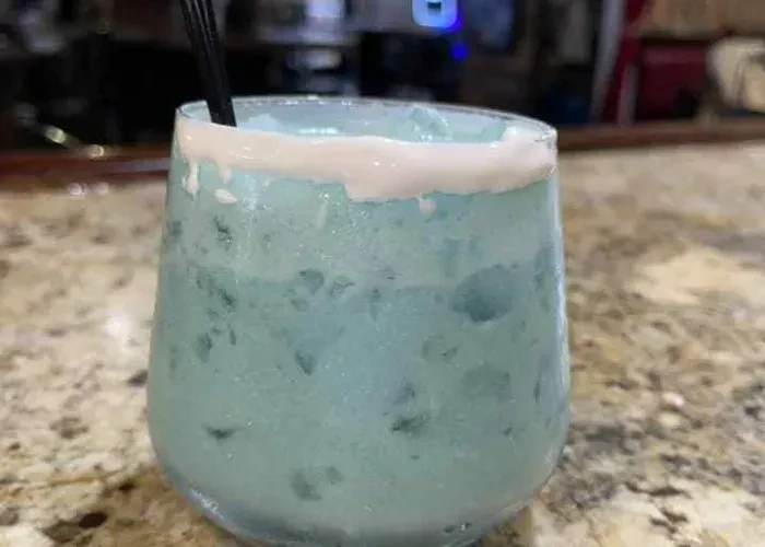Pale blue frozen drink with white rim and dark straw.