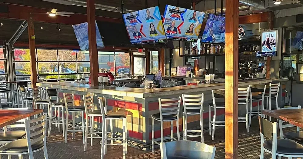 Modern sports bar interior with colorful striped bar, TVs, autumn trees.