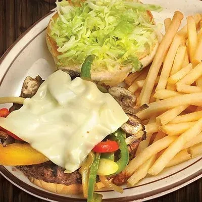 Open-faced burger with sautéed vegetables, melted cheese, and fries.