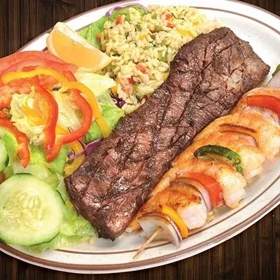 Grilled steak, shrimp skewer, rice, and salad on an oval plate.