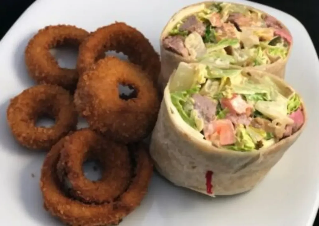 Onion rings and two halves of a filled wrap on a plate.