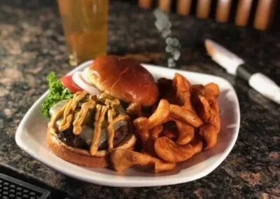 Open-faced burger with melted cheese, fries, and a drink.