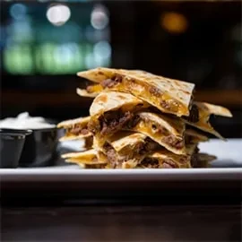 Stacked meat and cheese quesadilla triangles with creamy dipping sauce.