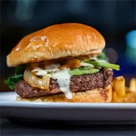 Gourmet beef burger with brioche bun, cheese, onions, and fries.