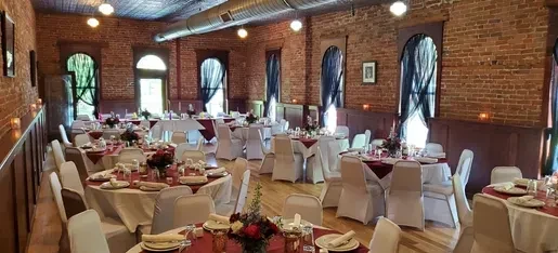 Formal dining room with exposed brick, high ceilings, and set tables.