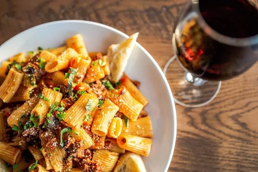 Rigatoni pasta with meat sauce, herbs, cheese, bread, and red wine.