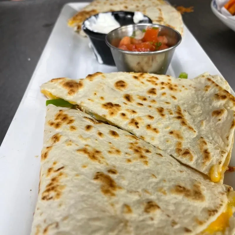 Grilled cheese and pepper quesadilla halves with sour cream and salsa.