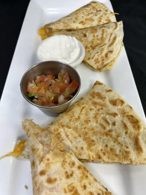 Four quesadilla triangles with melted cheese, sour cream, and salsa.