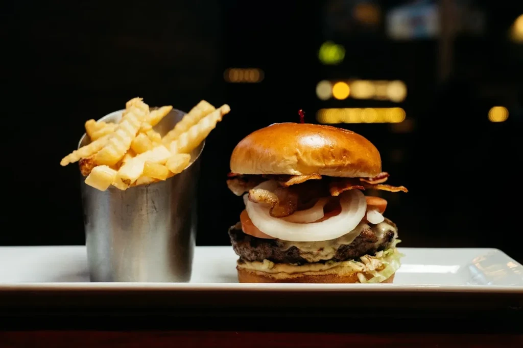 Close-up of a gourmet burger with bacon, cheese, and crinkle-cut fries.
