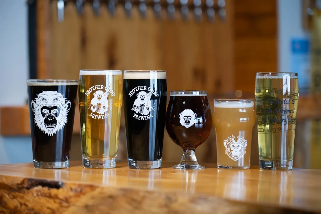 Six Brother Chimp Brewing beers and ciders on a rustic wooden bar.