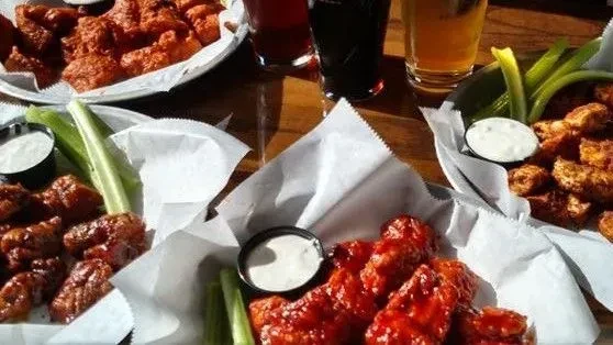 Two baskets of chicken wings, celery, dipping sauce, and beers.