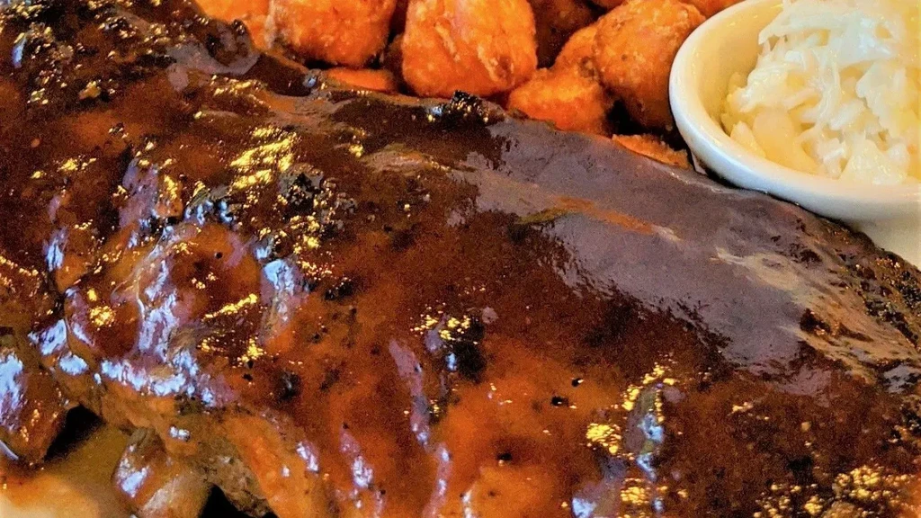 Dark, glossy barbecue ribs with sweet potato tots and creamy coleslaw.