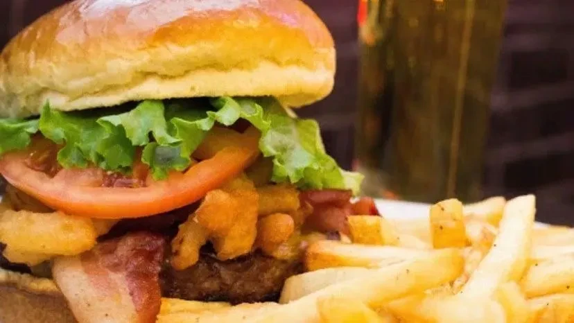 Burger with bacon, fried onions, and golden fries.