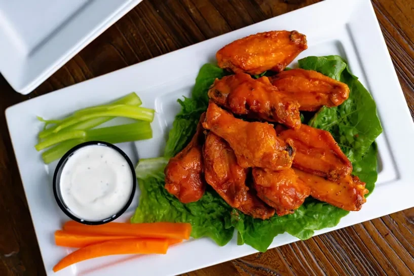 Buffalo chicken wings with celery, carrots, and dipping sauce.