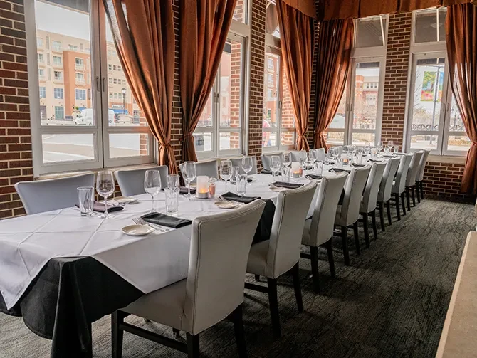 Elegantly set dining table in a brick-walled private room with city view.