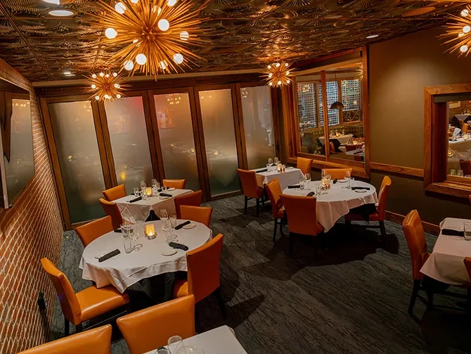 Upscale empty restaurant dining room with set tables and sputnik chandeliers.