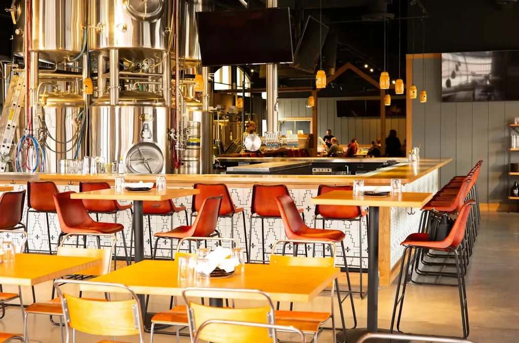 Modern brewery restaurant interior with visible stainless steel brewing tanks.