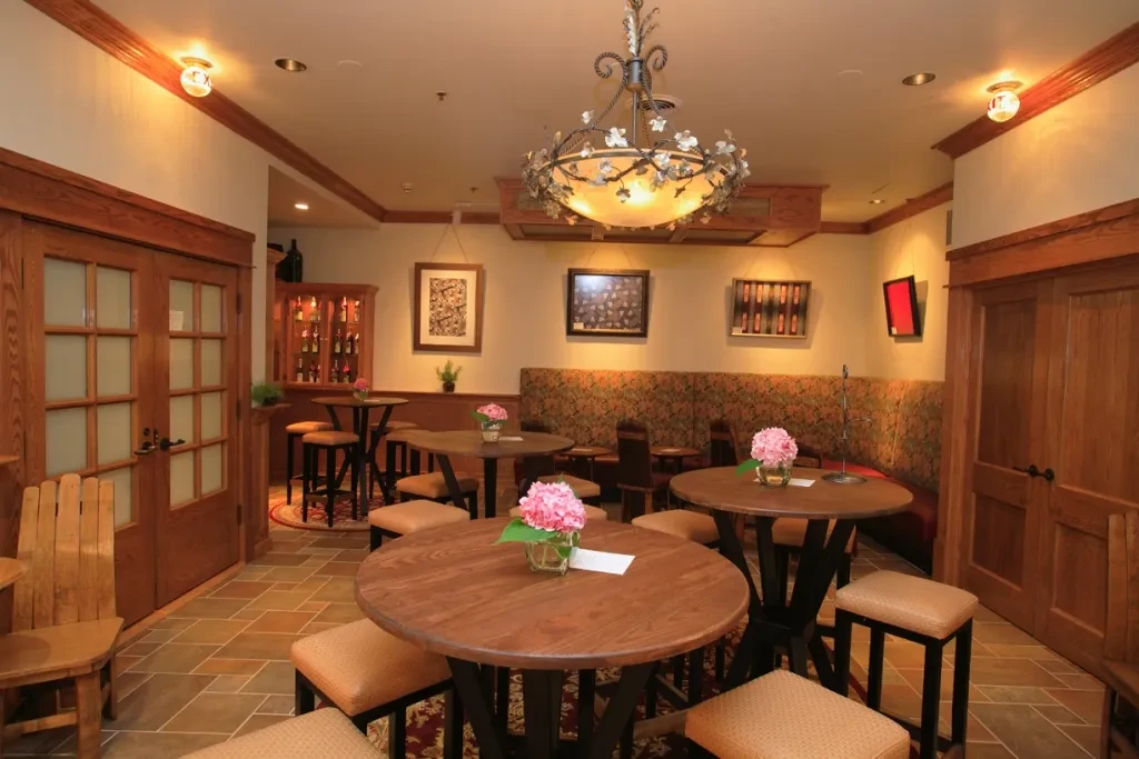 Elegant restaurant interior with tables, banquette, hydrangeas, ornate chandelier.