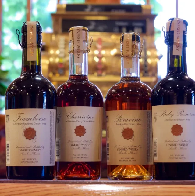 Four Lynfred Winery dessert wine bottles: raspberry, cherry, pear, and red.