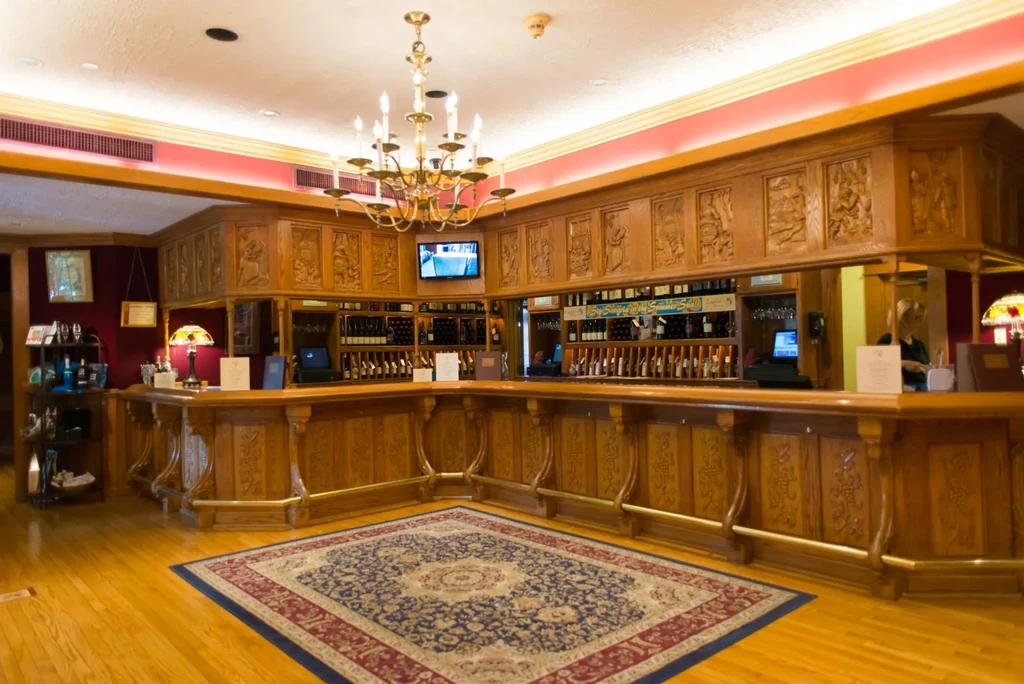Ornate U-shaped bar with wine dispensers in a restaurant interior.