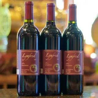 Three identical Lynfred 2010 Sangiovese red wine bottles.
