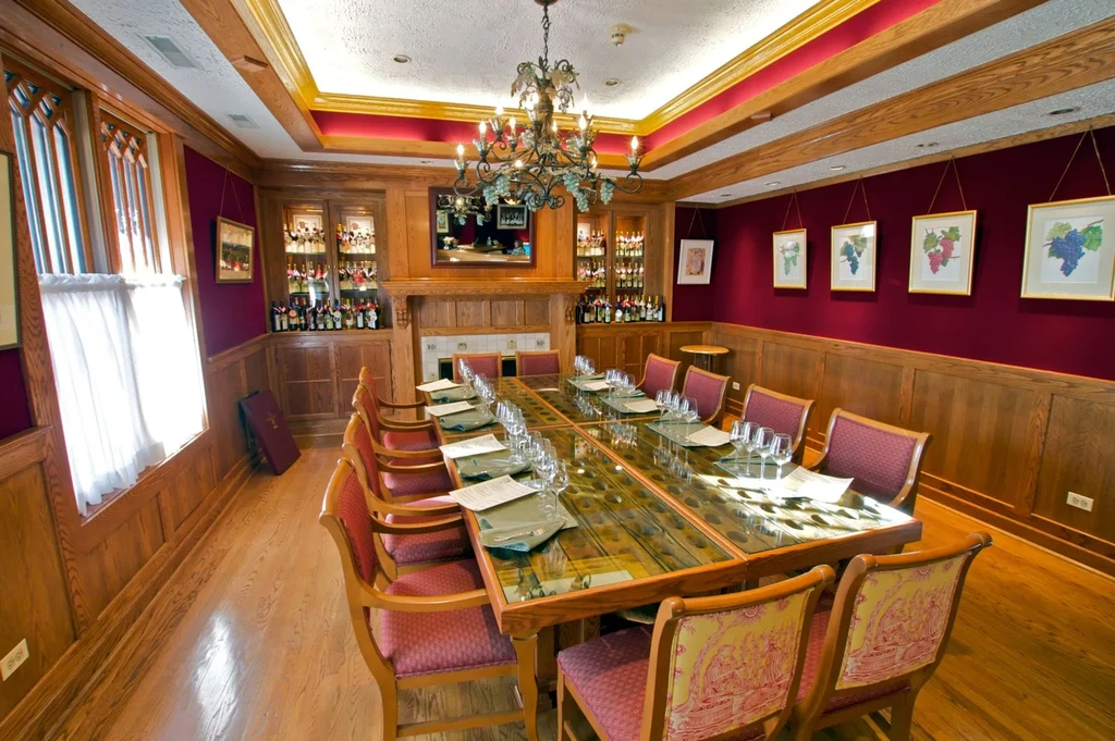 Private dining room with a long set table, wine bottles, and maroon walls.