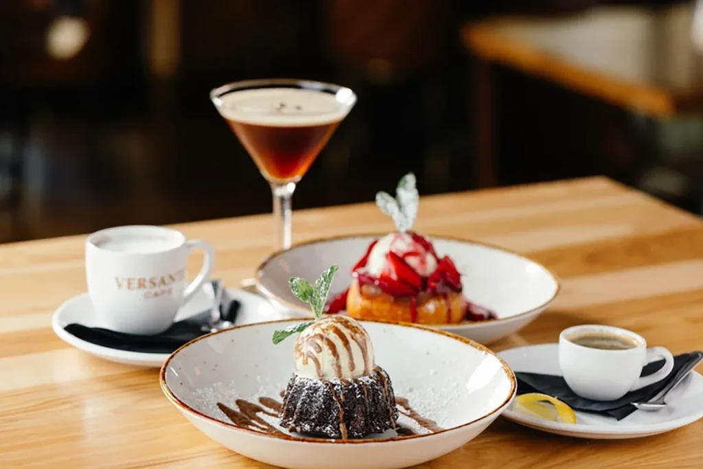 Chocolate lava cake, berry cake, and coffee drinks on a wooden table.