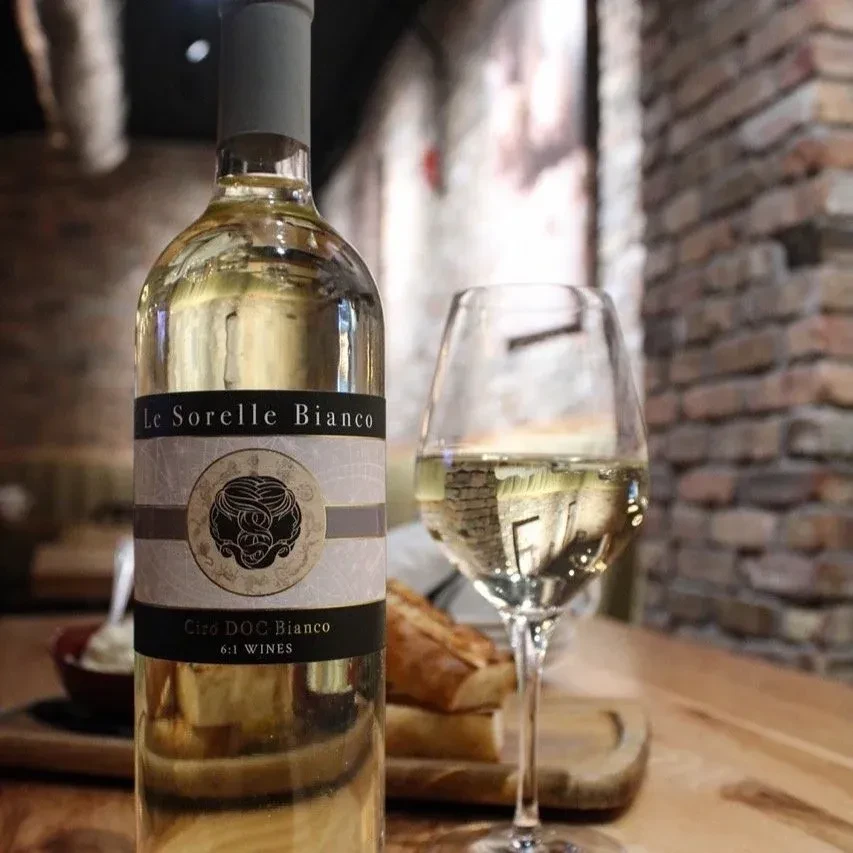 White wine bottle and full glass with bread on a rustic table.