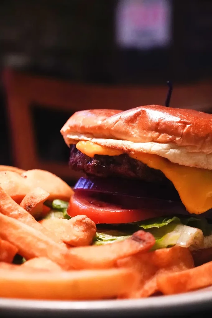 Cheeseburger with a skewer and a side of french fries.