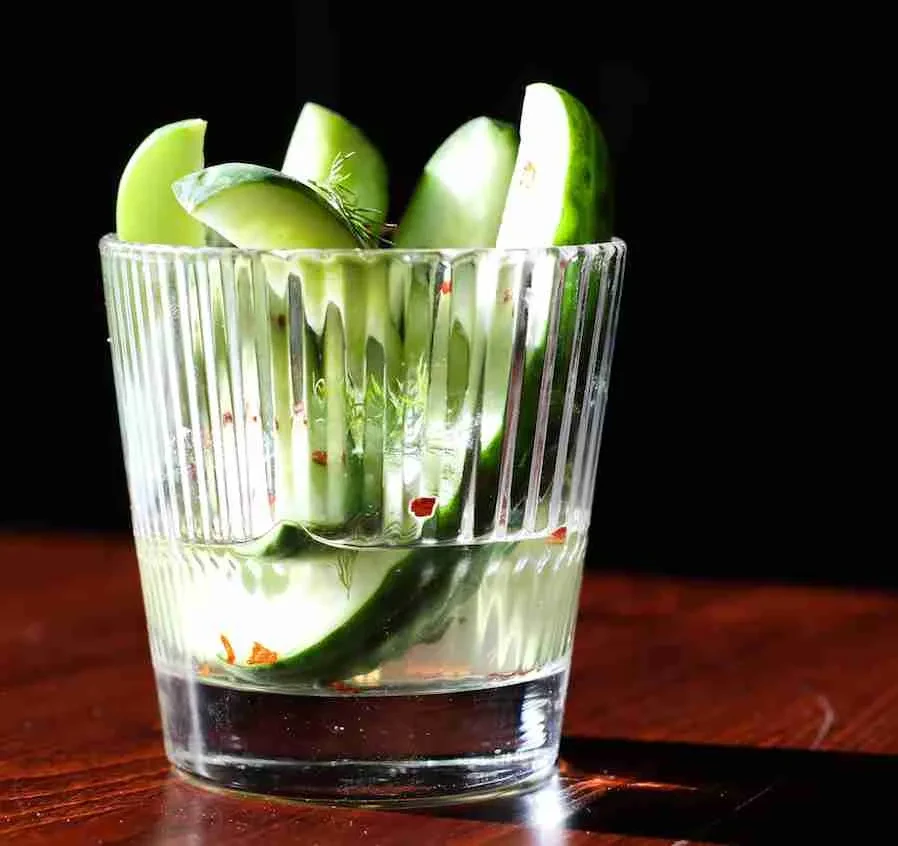 Ribbed glass filled with cucumber slices, dill, and red spice.
