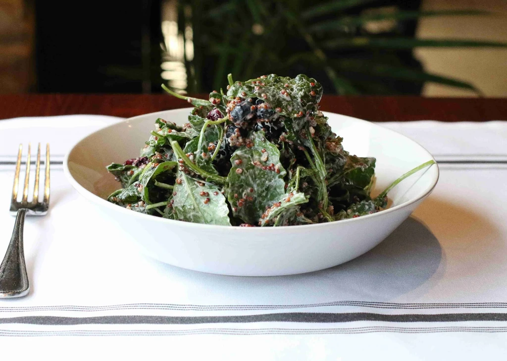Vibrant green salad with quinoa, berries, and creamy dressing.