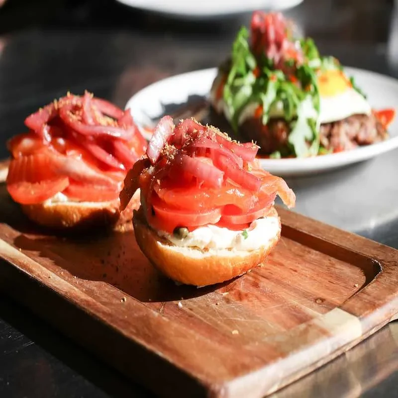 Open-faced bagels with cream cheese, tomatoes, onions, and capers.