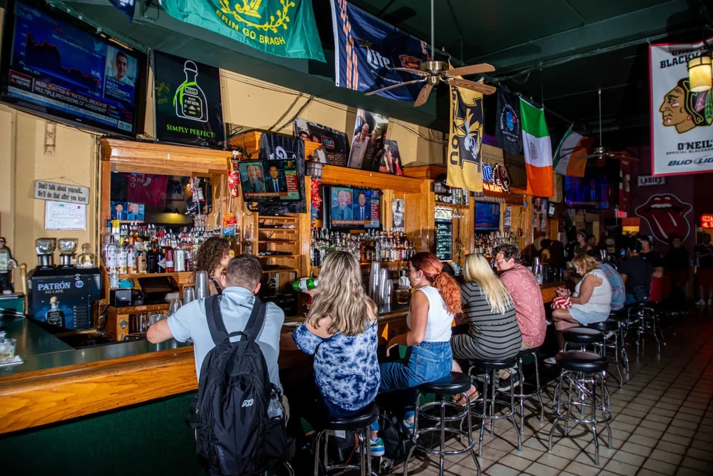 Interior of a lively bar with patrons, a bartender, and a stocked counter.
