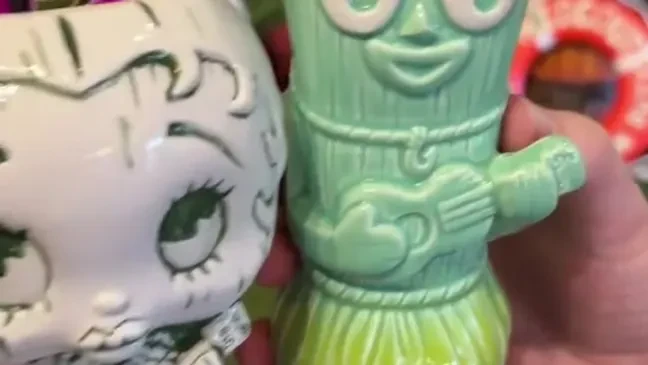 Two stylized tiki mugs: one white, one light green.